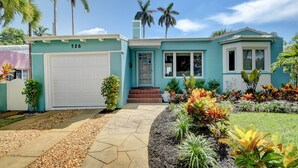 A two-story house with a garage, a front porch, and a well-maintained garden with various plants and a pathway.