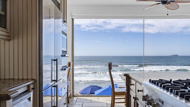 A kitchen with a view of the ocean, a ceiling fan, and a gas stove. - Luxury Oceanfront Villa w/ Resort Style Amenities (Oceanside)