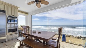 A kitchen with a large window overlooking the ocean, a dining table, and a ceiling fan. - Luxury Oceanfront Villa w/ Resort Style Amenities (Oceanside)