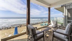 A balcony with a view of the ocean, furnished with chairs and a table. - Luxury Oceanfront Villa w/ Resort Style Amenities (Oceanside)