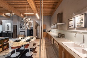 A modern kitchen with a marble countertop, wooden cabinets, and a hanging light fixture.