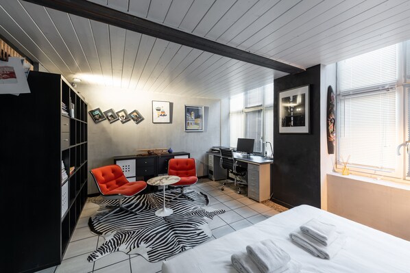 A modern room with a bed, a desk, a chair, a zebra rug, and a bookshelf. - Art & Soie - Appt d’exception avec terrasse – Croix-Rousse (Lyon)