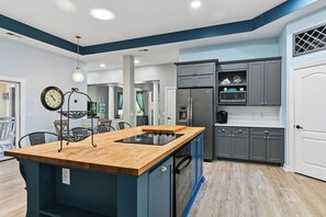 A modern kitchen with a central island, built-in appliances, and a dining area with chairs. - Beautiful Home w/ Pool & Game Room (Hilton Head Island)