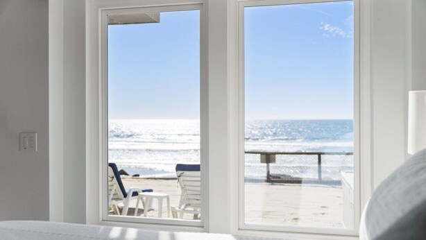A bedroom with a large window overlooking a beach. - Oceanfront Home w/ Panoramic Views & Private Beach (Oceanside,)