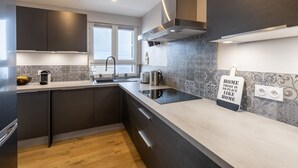 A modern kitchen with dark cabinets, a stainless steel range hood, and a sign that reads "HOME THERE IS NO PLACE LIKE HOME." - Orpin - superbe appartement rénové 2 personnes avec grande terrasse plein sud, belle vue (Font-Romeu)