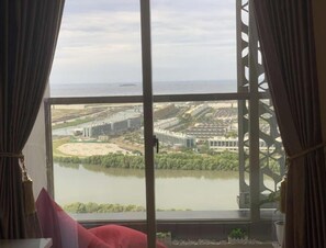 Enjoy a serene view of the water and cityscape from this room's large window, framed by a decorative metal lattice.