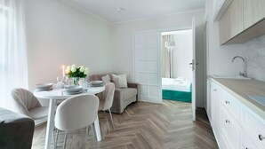 A modern, well-lit room with a dining area, a sofa, and a kitchen. - Elite Apartments Rezydencja Wintera (Gdansk)