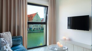 A modern hotel room with a large window offering a view of a historic building and a canal. - Elite Apartments Rezydencja Wintera (Gdansk)