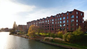 A modern multi-story hotel with a red brick facade, large windows, and a canal in the foreground. - Elite Apartments Rezydencja Wintera (Gdansk)