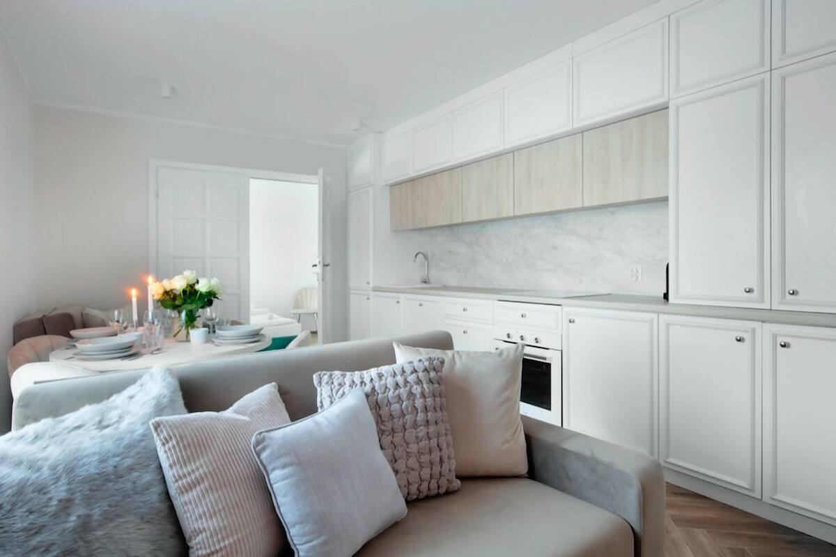 A modern kitchen with white cabinetry, a marble countertop, and a built-in oven.