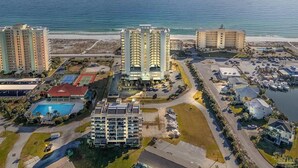 An aerial view of a coastal hotel complex with multiple high-rise buildings, a marina, and a swimming pool. - Beauty on the Beach - Emerald Dolphin 3B w/Amazing Gulf Views. (Pensacola Beach)