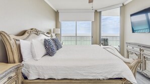 A hotel room with a large bed, a ceiling fan, a TV, and a balcony with a view. - Beauty on the Beach - Emerald Dolphin 3B w/Amazing Gulf Views. (Pensacola Beach)