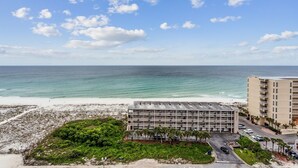 A beachfront hotel with a parking lot, a pool area, and a view of the ocean. - Beauty on the Beach - Emerald Dolphin 3B w/Amazing Gulf Views. (Pensacola Beach)