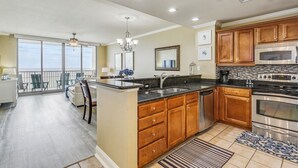 A spacious kitchen with wooden cabinets, a large island, and a view to the outside. - Beauty on the Beach - Emerald Dolphin 3B w/Amazing Gulf Views. (Pensacola Beach)