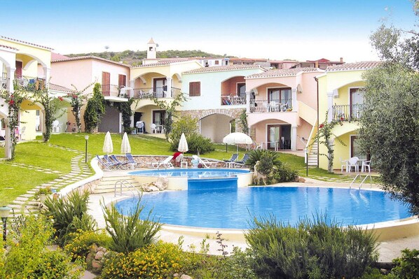A hotel with a central swimming pool, multiple balconies, and a lush garden.