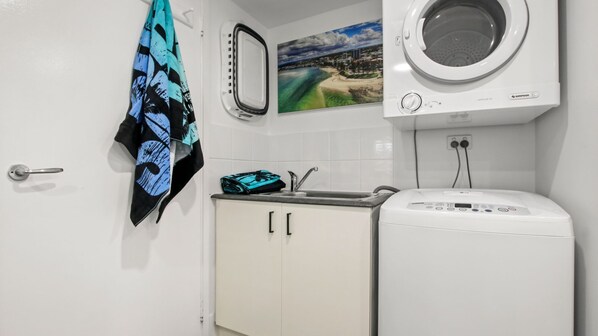 A compact kitchen with a washing machine, a sink, and a towel hanging on the door.
