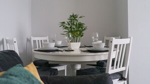 A dining table with white chairs, a potted plant, and white tableware. - Hawthorn- Great 2 bed home in Ashington, Northumberland (Ashington)