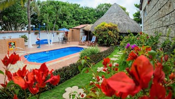 Una piscina al aire libre, sombrillas, sillones reclinables de piscina