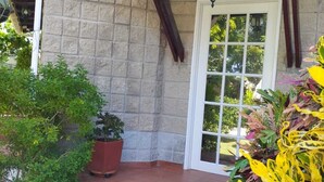 A stone building with a wooden porch, a potted plant, and a door with a window. - Portoazul Casa de Playa (Puerto Colombia)