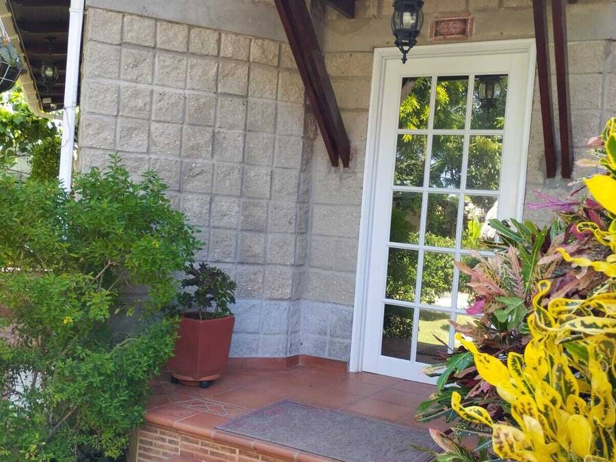 A stone building with a wooden porch, a potted plant, and a door with a window.