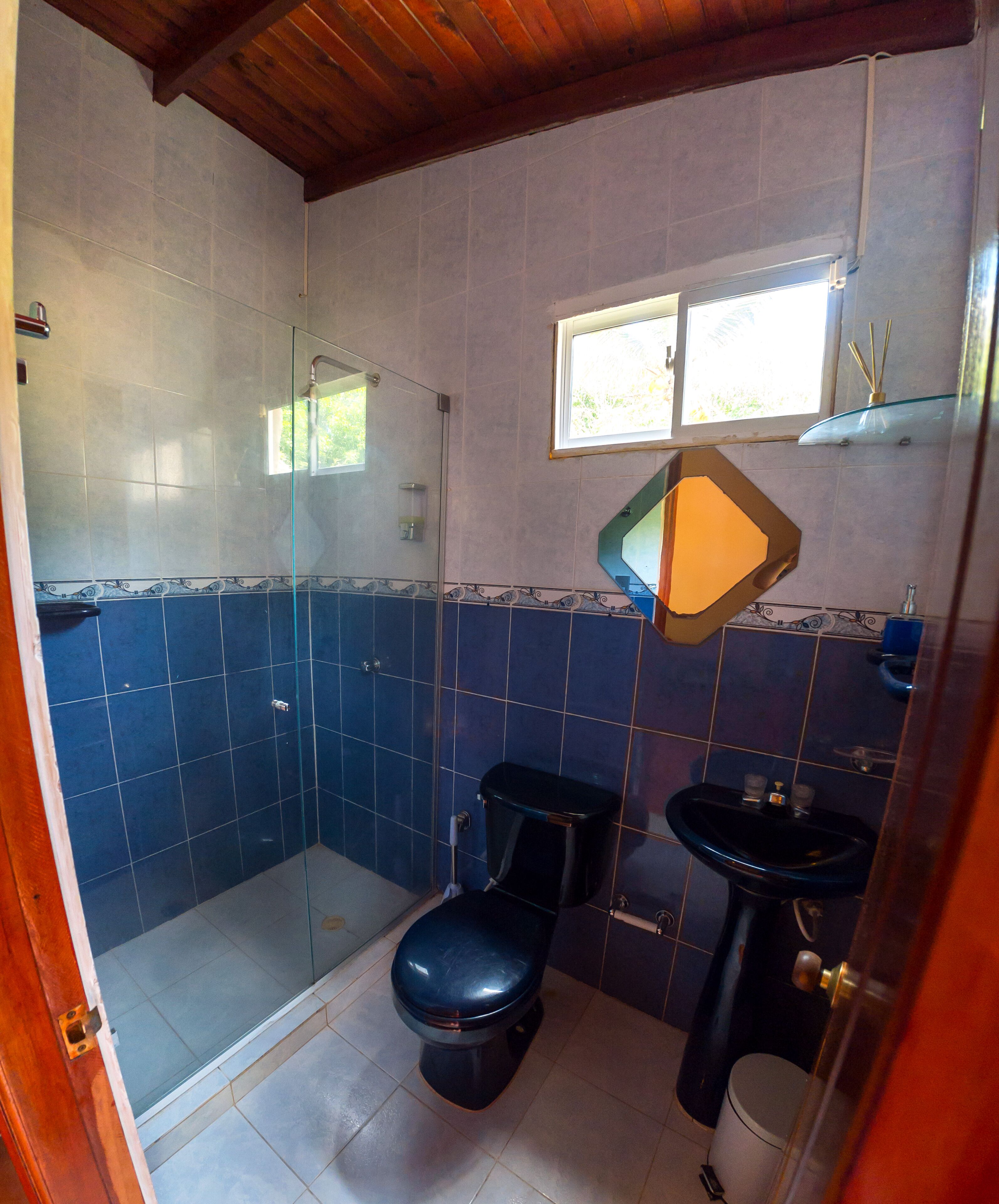 A bathroom with a glass shower enclosure, a toilet, and a sink.