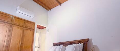 A bedroom with a wooden ceiling, a bed, a nightstand, and a wardrobe.