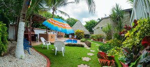 A tropical garden with a pool, white chairs, and a colorful umbrella. - Portoazul Casa de Playa (Puerto Colombia)