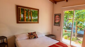 A bedroom with a bed, a ceiling fan, a painting, a poster, and a view of the outdoors. - Portoazul Casa de Playa (Puerto Colombia)