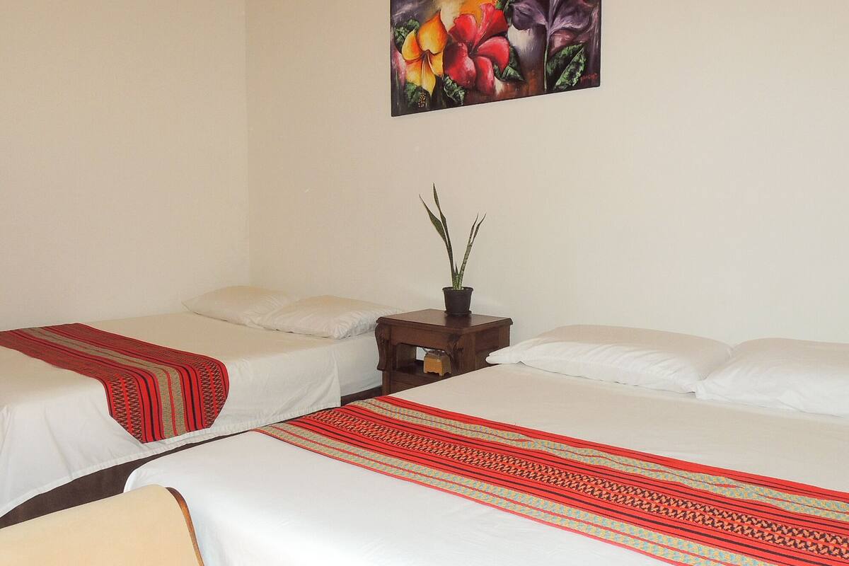 Ein Hotelzimmer mit zwei Einzelbetten, einem Nachttisch mit Topfpflanze und einem Bild an der Wand.