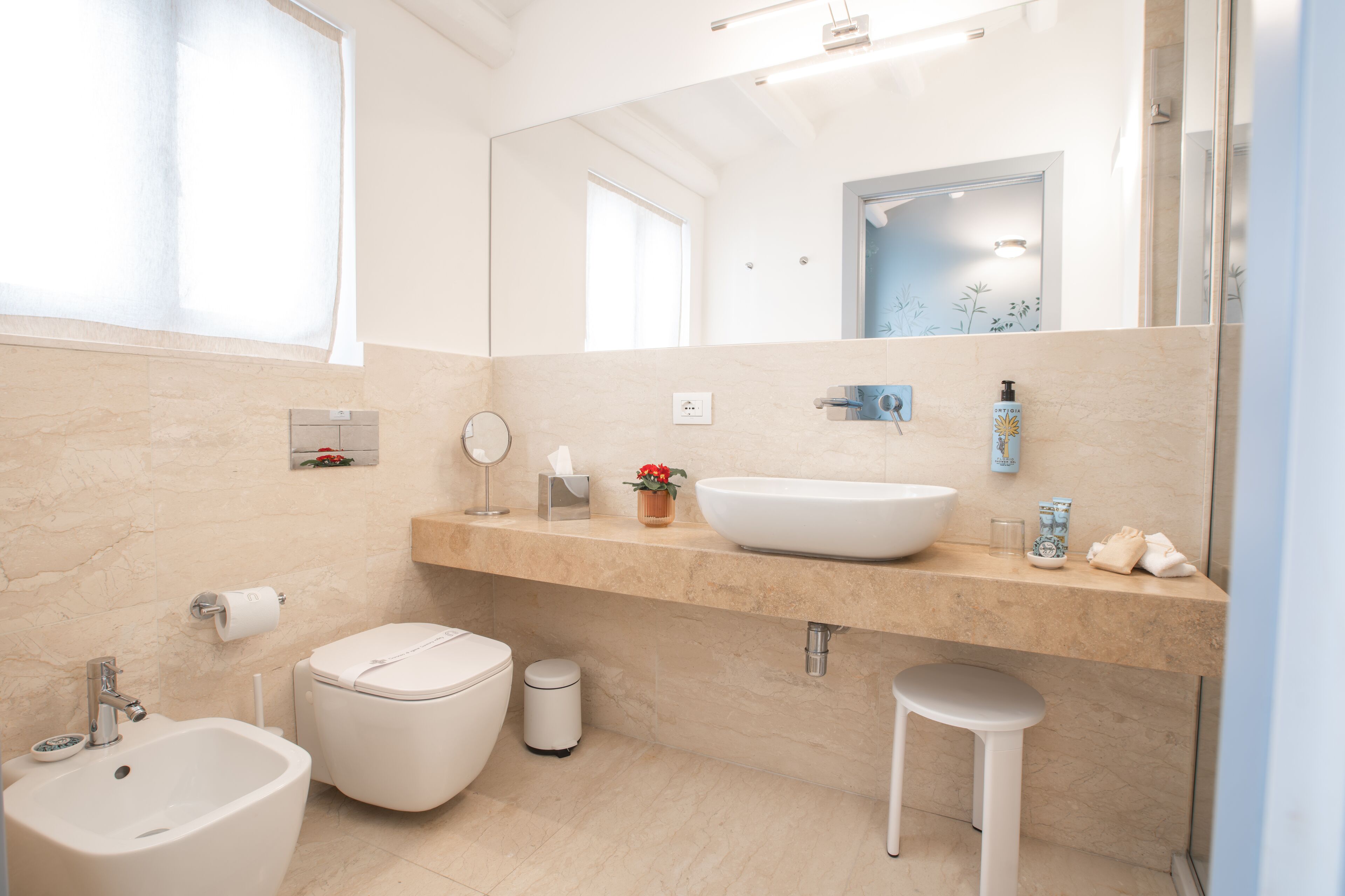 Une salle de bain moderne avec un grand lavabo, des toilettes, un bidet et un miroir.