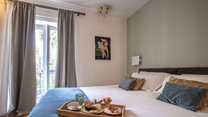 A neatly made bed with a tray of breakfast items, a painting on the wall, and a view of the outdoors through the window. - Archè Design Rooms and Suites (Palermo)