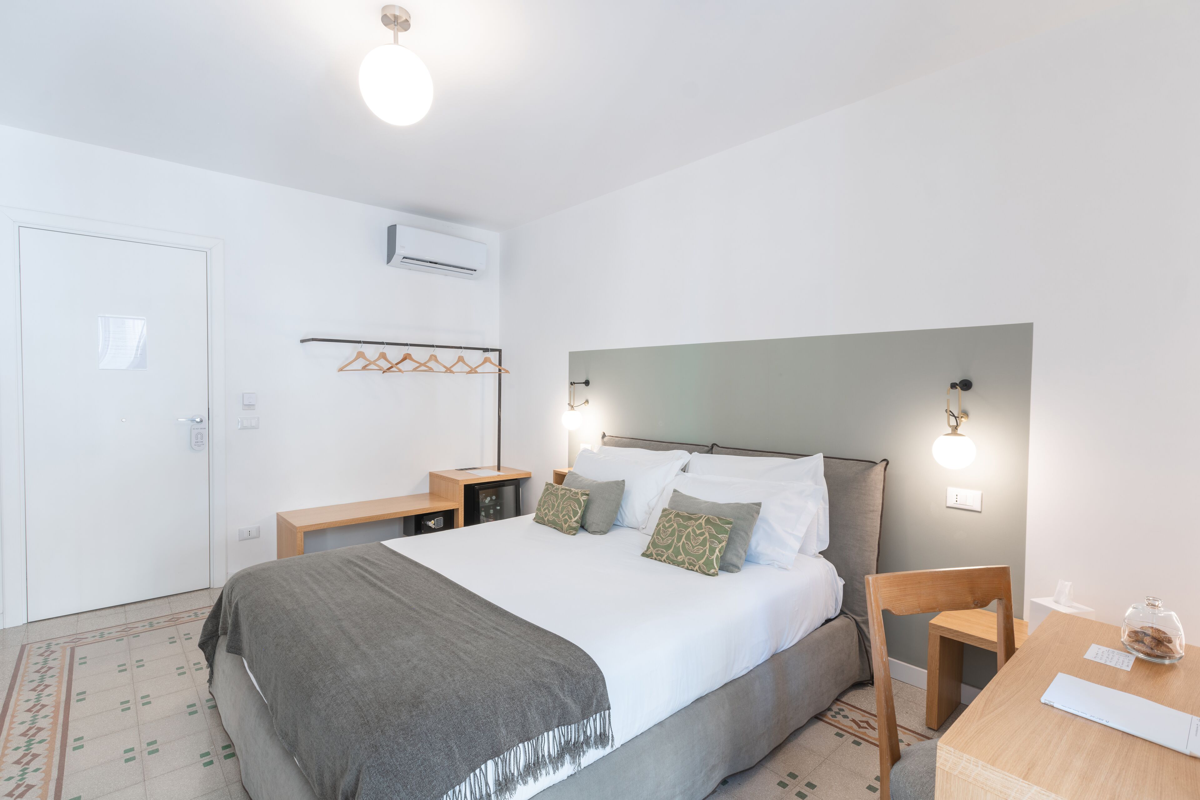Quarto bem arrumado com uma cama grande, mesas de cabeceira, uma escrivaninha e uma cadeira.