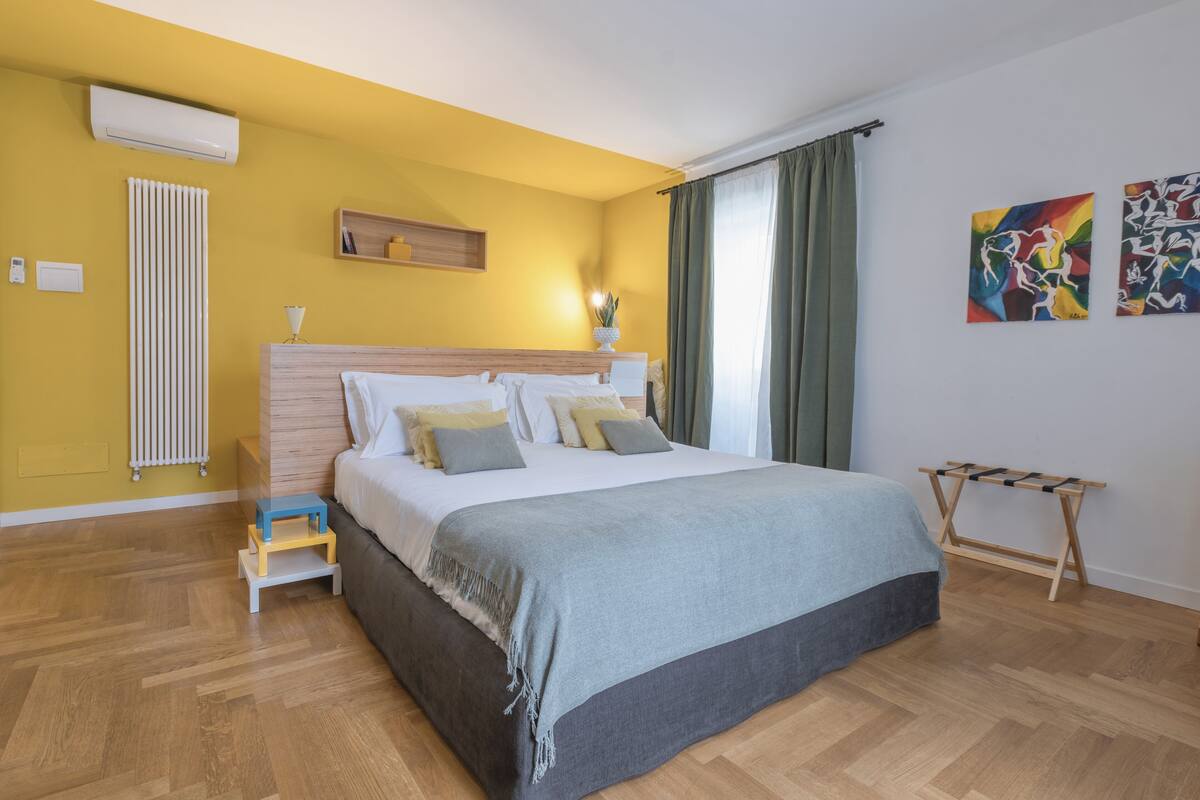 A bedroom with a bed, bedside table, and a radiator.