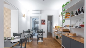 A modern kitchen with a dining area, featuring a wooden herringbone floor, grey chairs, and a white dining table. - Archè Design Rooms and Suites (Palermo)