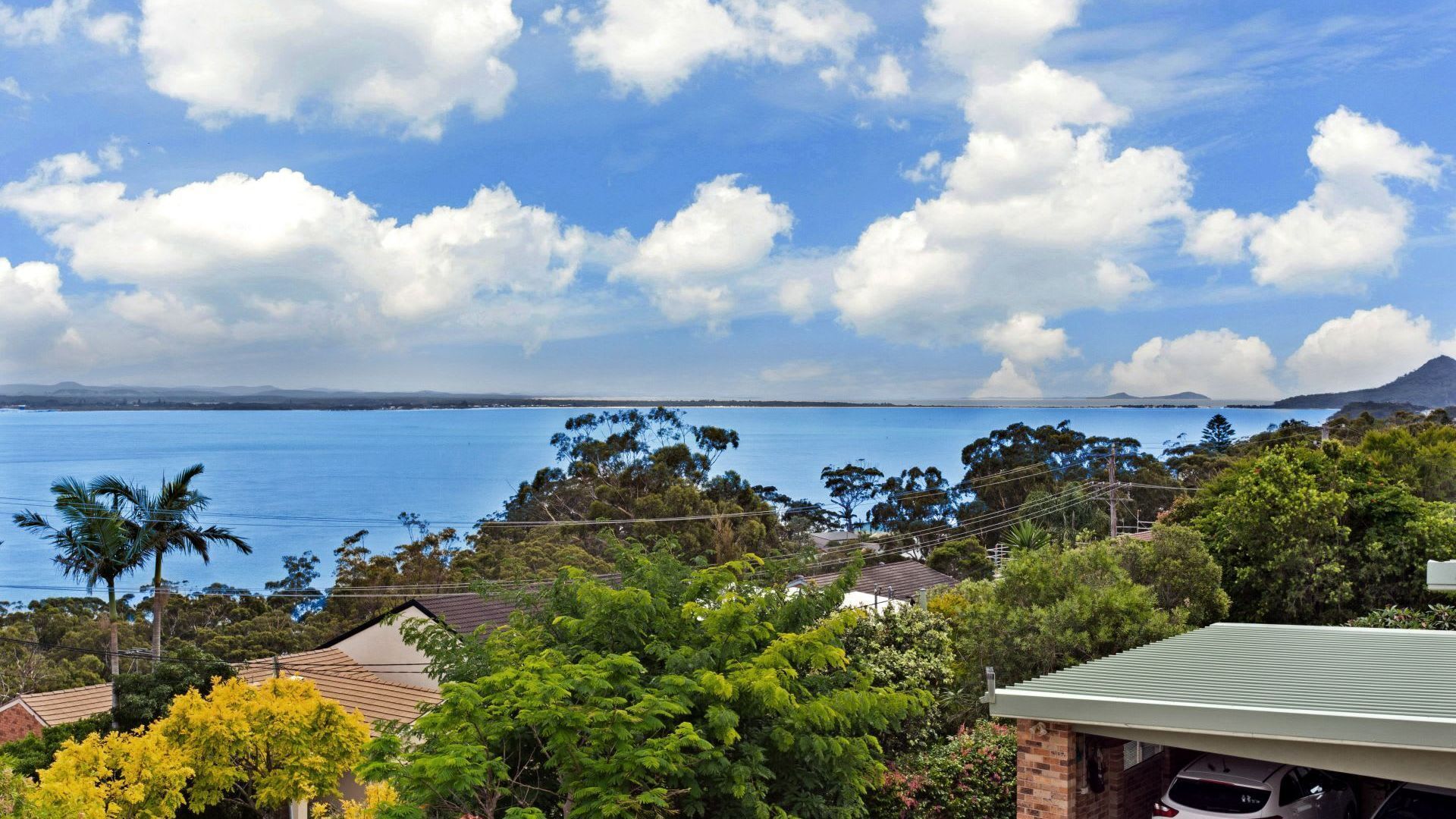 A coastal view with a clear sky, a body of water, and a distant mountain.