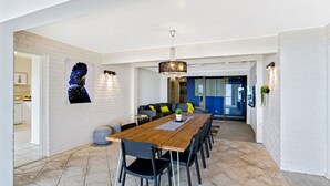 A modern dining area with a wooden table, black chairs, and a chandelier. - The Bay- Stunning water views (Nelson Bay)
