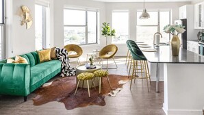 A modern living room with a green sofa, a dining area with bar stools, and a kitchen island. - GoodLUXCharm Luxury 2B2B In Deep Ellum Rftp Pool (Dallas)