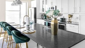 A modern kitchen with a central island, bar stools, white cabinets, and a vase with flowers. - GoodLUXCharm Luxury 2B2B In Deep Ellum Rftp Pool (Dallas)