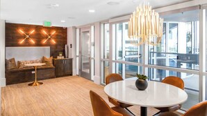 A modern office space with a round table, orange chairs, a wooden accent wall, and a large window with a view. - GoodLUXCharm Luxury 2B2B In Deep Ellum Rftp Pool (Dallas)