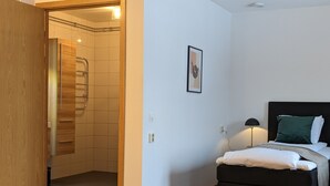 A bedroom with a bed, a bedside table, a lamp, and a framed picture on the wall. - Hotell Bro (Kristinehamn)