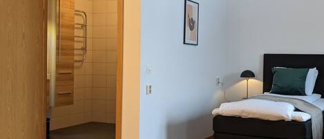 Un dormitorio con una cama, una mesita de noche, una lámpara y un cuadro en la pared.