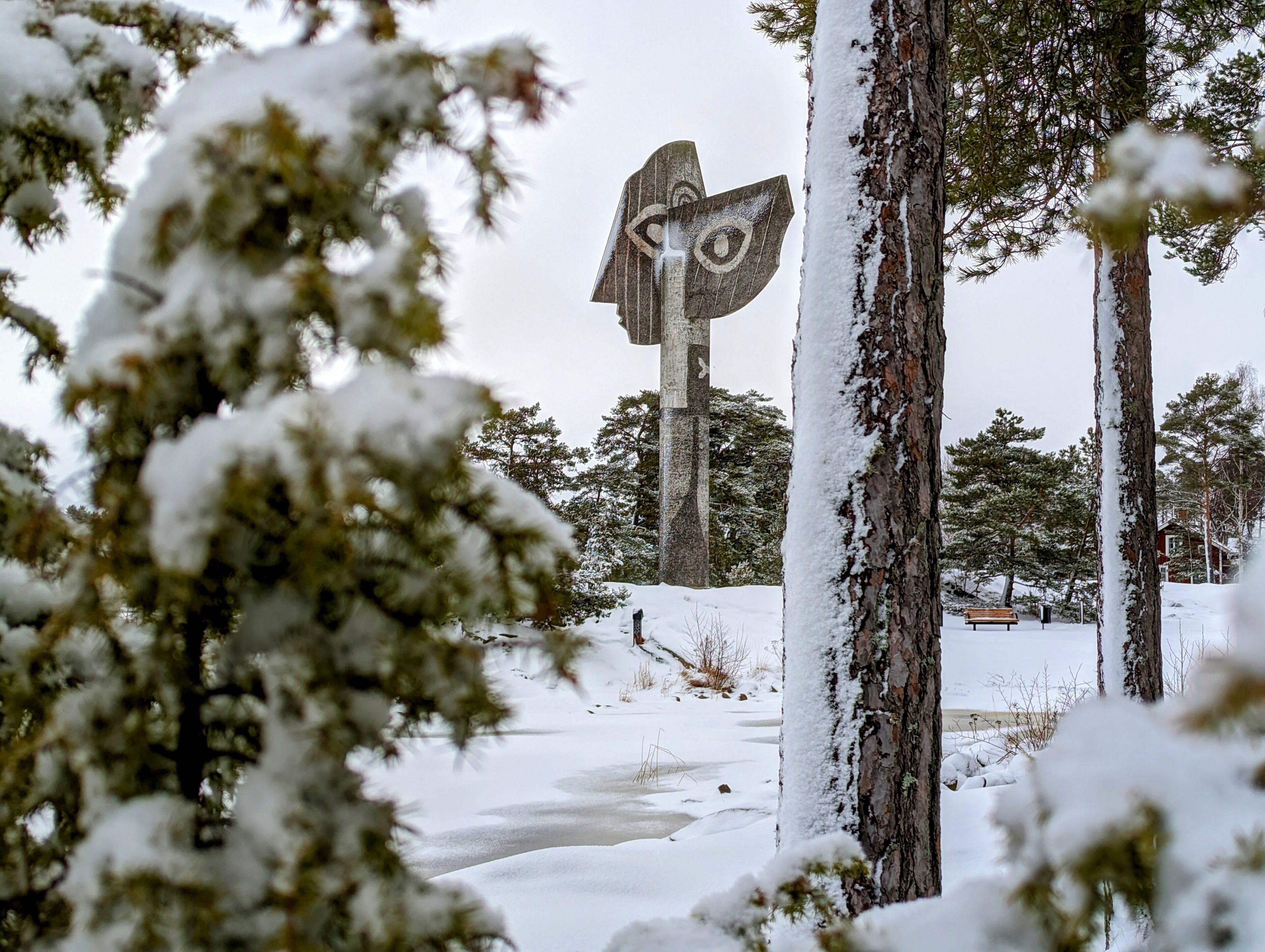 A snow-covered outdoor area with a wooden sculpture in the background.