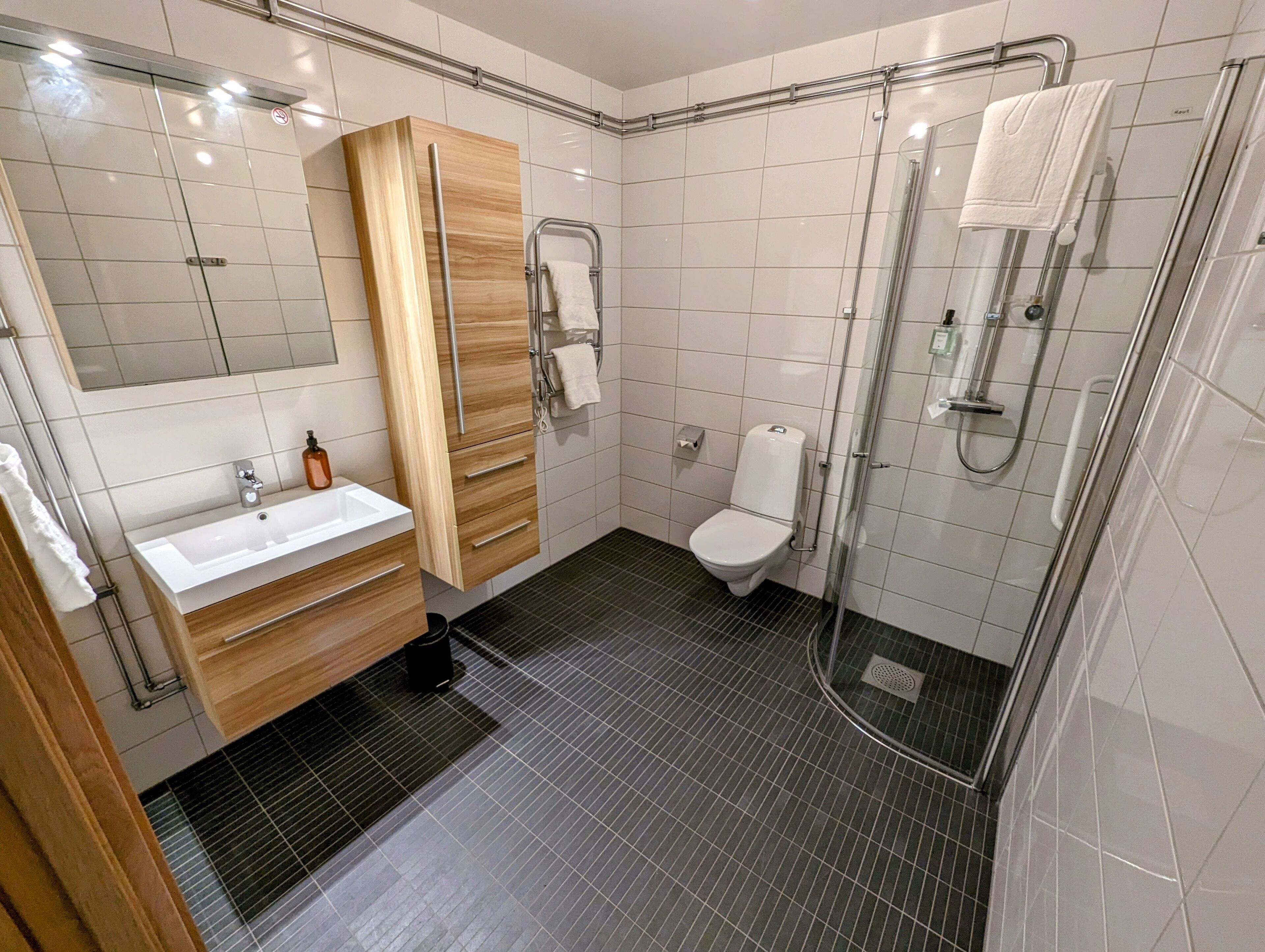 Un baño moderno con lavamanos, inodoro y ducha con mampara de vidrio.