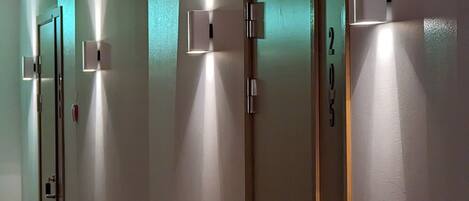 A hallway with doors, each with a light switch and a lock.