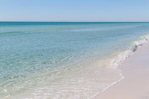 A beach with clear shallow waters and a sandy shore.