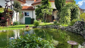 A house with a garden, a pond, and a stone wall. - Vacation apartment Freiburg surroundings - FELDSCHLÖSSCHEN in March (March)