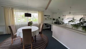 A dining area with a round table, chairs, a vase with flowers, and a view of greenery outside. - Vacation apartment Freiburg surroundings - FELDSCHLÖSSCHEN in March (March)