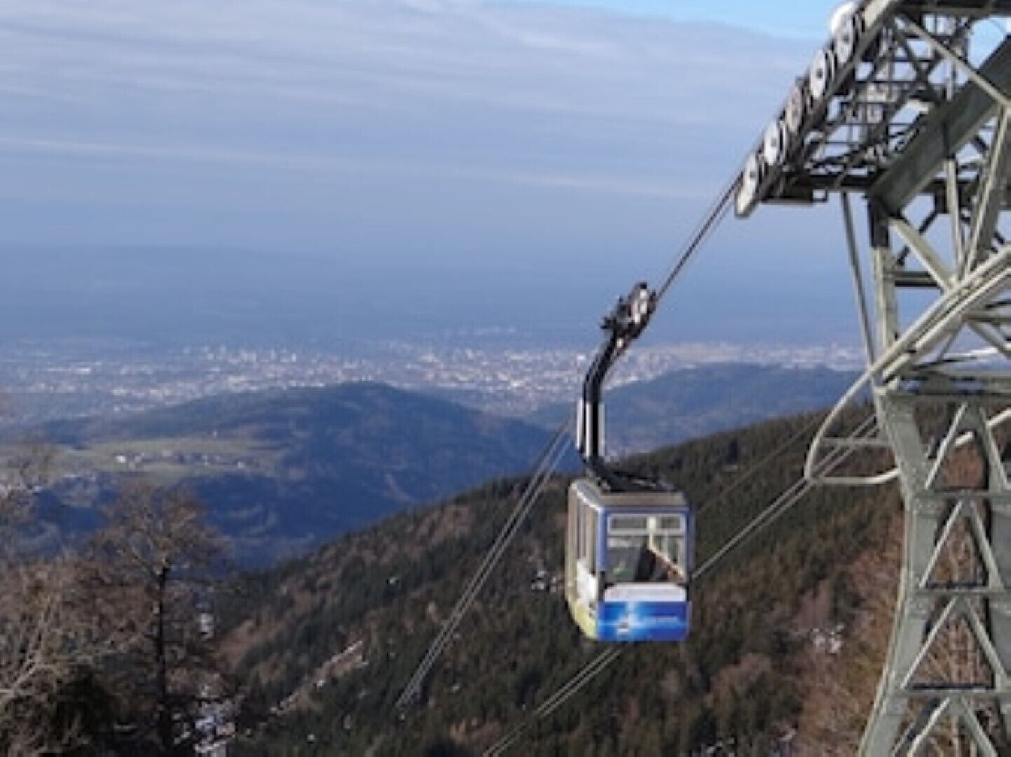 A cable car system with a cable car suspended between two towers, overlooking a mountainous landscape.
