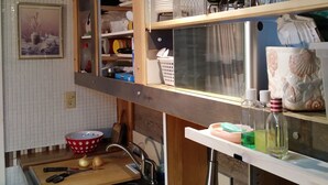 Uma cozinha compacta com pia, bancada de madeira e um suporte para panelas suspenso.