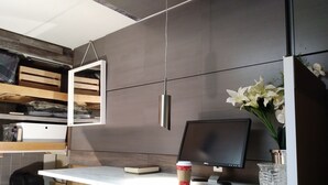 Um espaço de escritório moderno com uma mesa, computador, chávena de café e um vaso de flores.